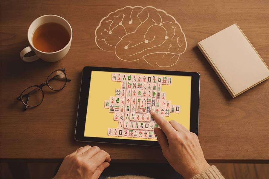 Person spielt Mahjong Solitär auf Tablet als ruhiges Gehirntraining
